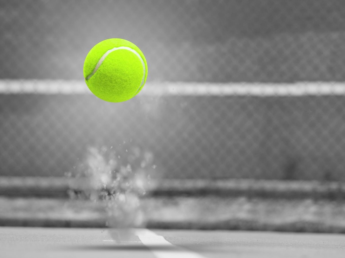 imagem em câmera lenta de uma bola de tênis depois de quicar no chão, com um fundo acinzentado